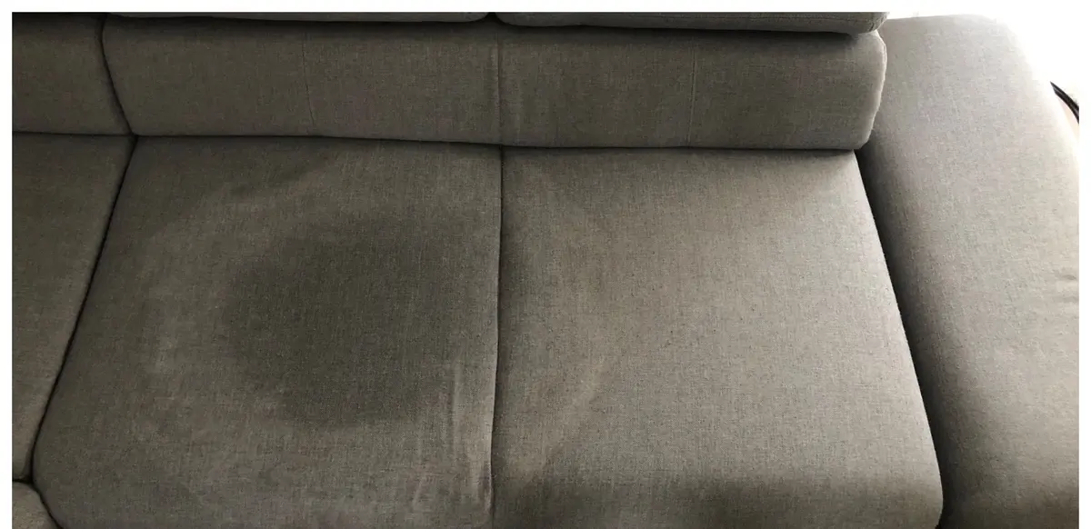 Szara sofa przed praniem — ciemna plama na siedzisku. Pranie kanapy Rybnik, SofaGo