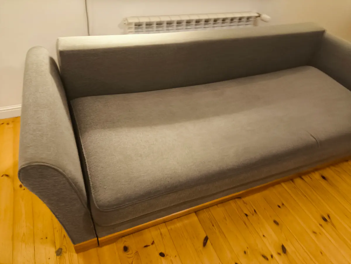 Szara sofa z zaokrąglonymi podłokietnikami po praniu ekstrakcyjnym — tkanina bez plam, kolor odzyskany. Pranie kanapy Szczecin, SofaGo