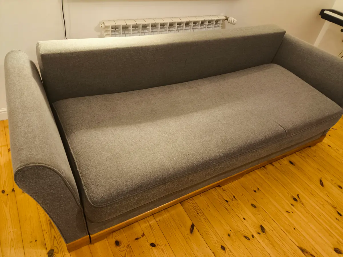 Szara sofa z zaokrąglonymi podłokietnikami po praniu ekstrakcyjnym — tkanina bez plam, kolor odzyskany. Pranie kanapy Warszawa, SofaGo