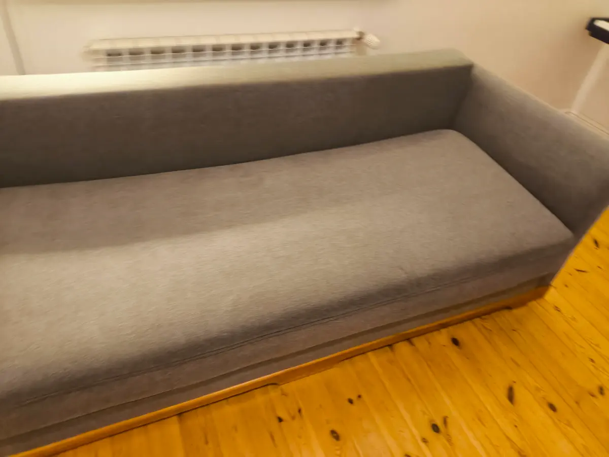Szara sofa z zaokrąglonymi podłokietnikami po praniu ekstrakcyjnym — tkanina bez plam, kolor odzyskany. Pranie kanapy Zabrze, SofaGo